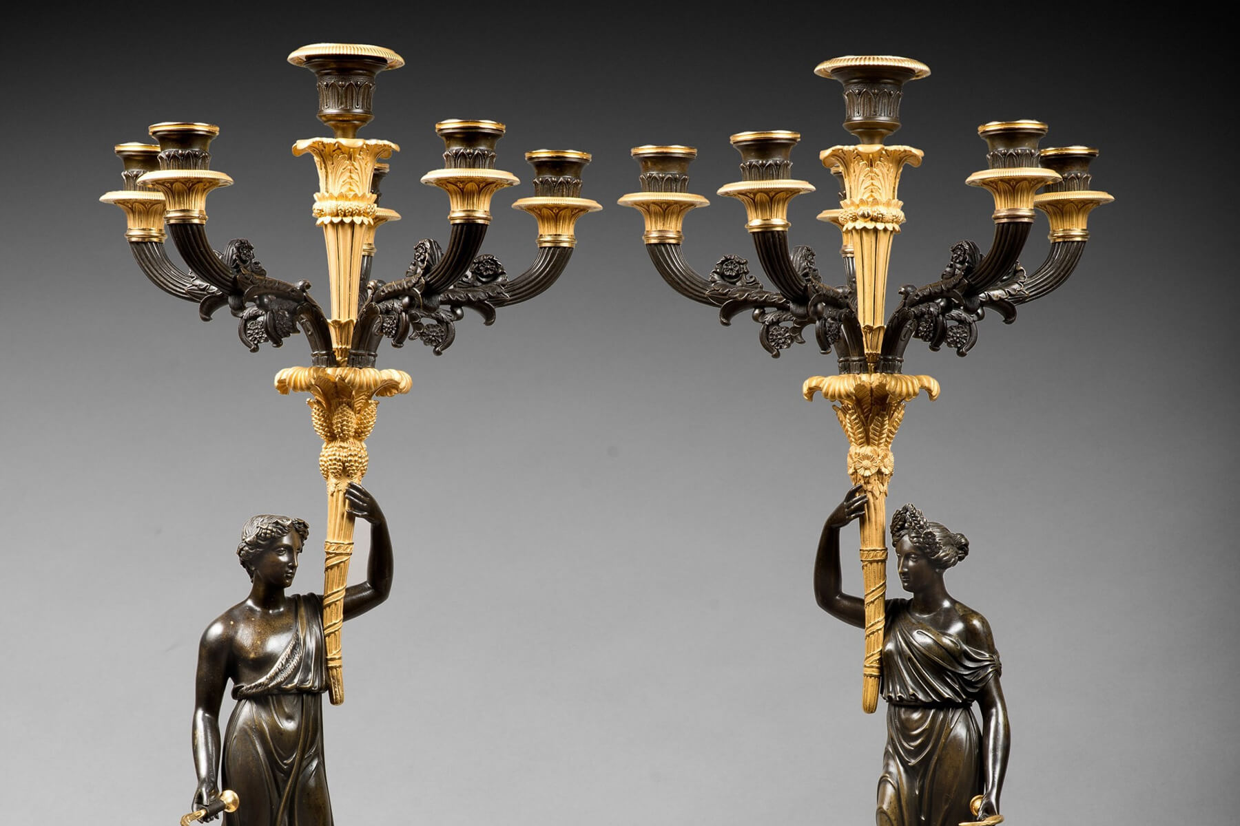 An empire patinated and gilded bronze pair of candelabras